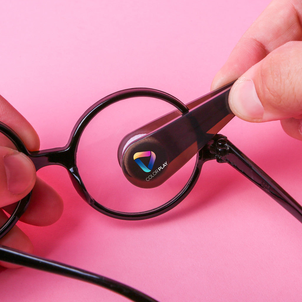 Close-up of hands using a custom branded eyeglass cleaner to clean round black eyeglass lenses