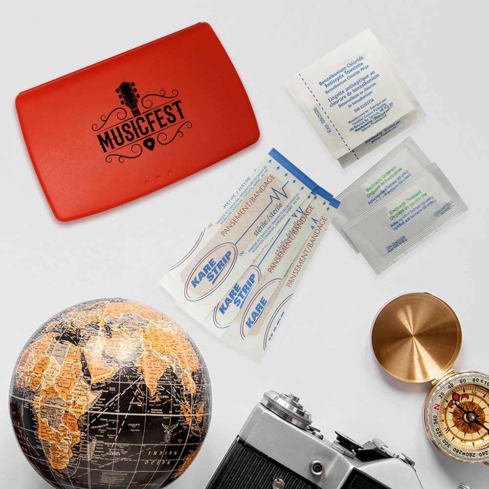 Red travel first aid kit with "MUSICFEST" logo, surrounded by bandages, antiseptic wipes