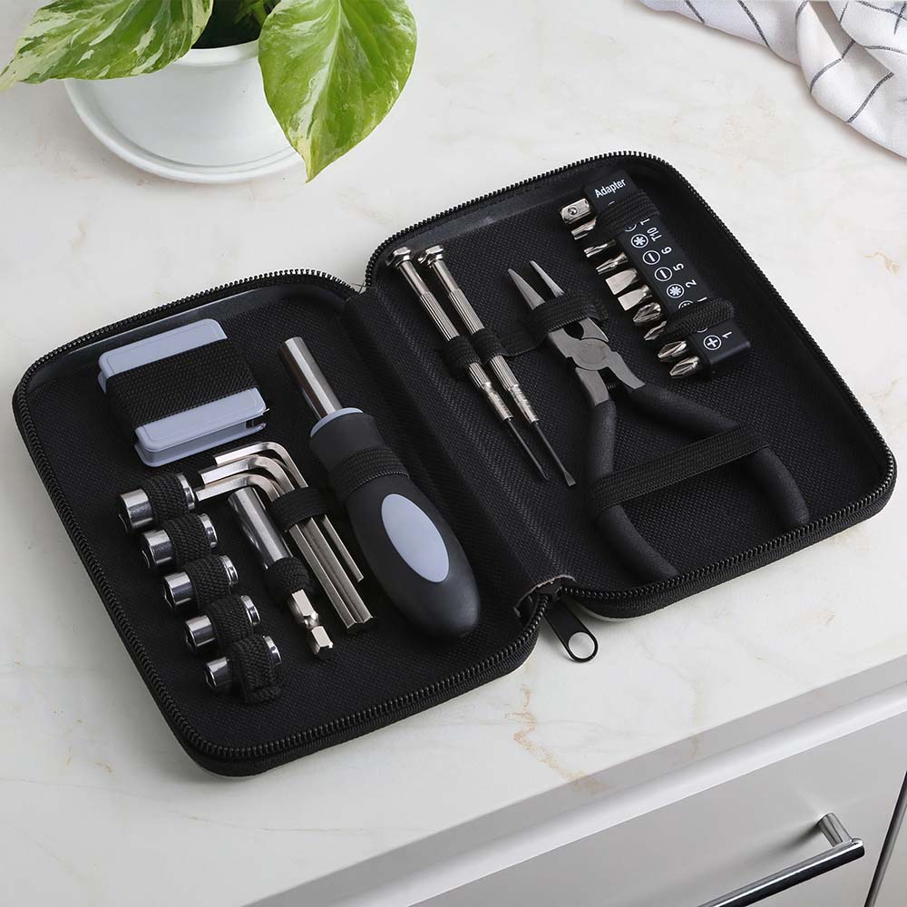 Open black zippered tool kit case neatly arranged with various hand tools including a screwdriver handle, Allen keys, sockets, pliers, tweezers, mini screwdrivers, and assorted screwdriver bits on a marble surface.
