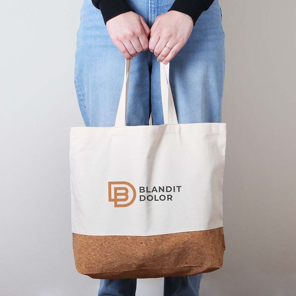 Person holding a beige canvas tote bag with cork bottom and custom logo