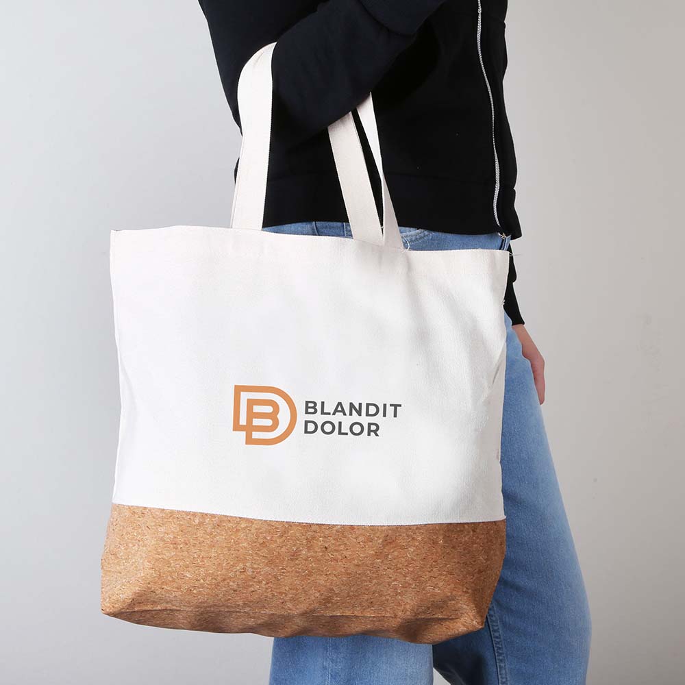 Side view of person carrying a beige canvas tote bag with cork bottom and custom logo
