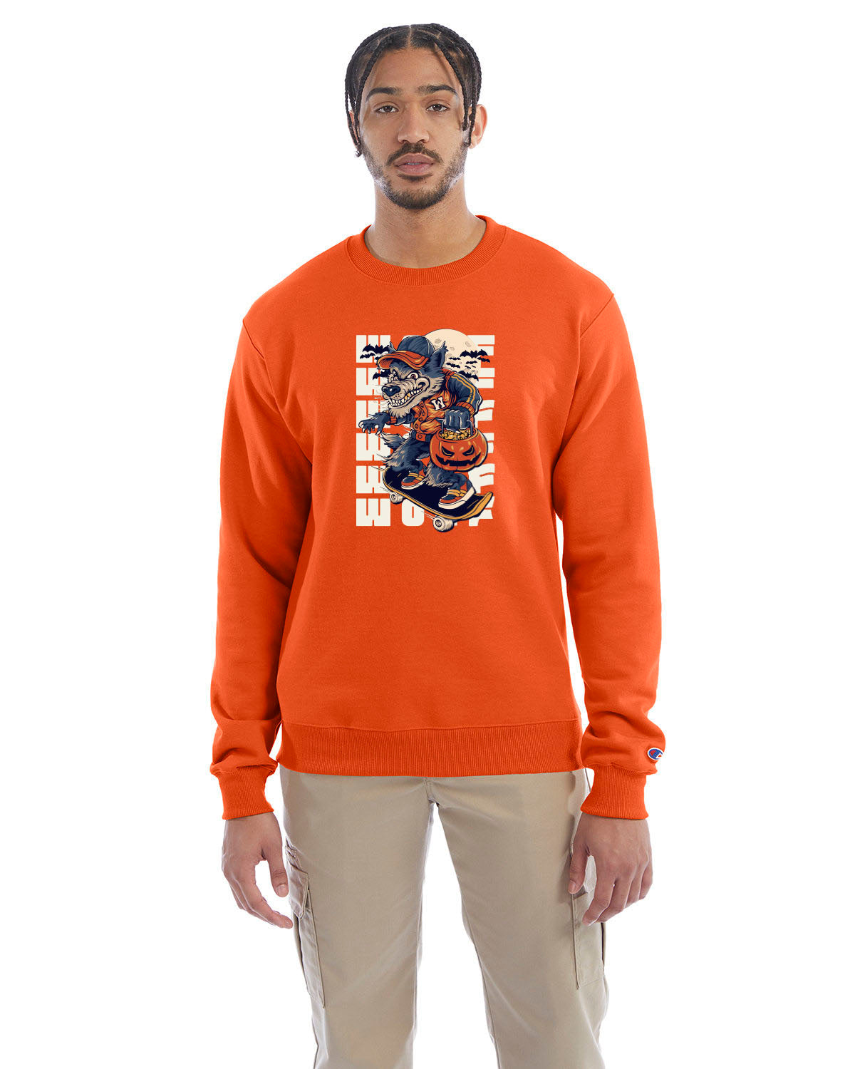 Orange crewneck sweatshirt with a Halloween-themed graphic of a cartoon werewolf skateboarding with a pumpkin basket, worn by a model in beige pants.