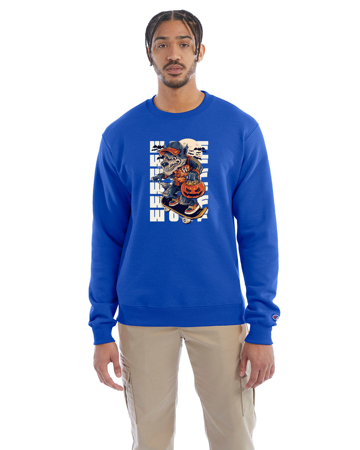 Royal blue crewneck sweatshirt with a Halloween-themed graphic of a cartoon werewolf skateboarding with a pumpkin basket, worn by a model in beige pants.