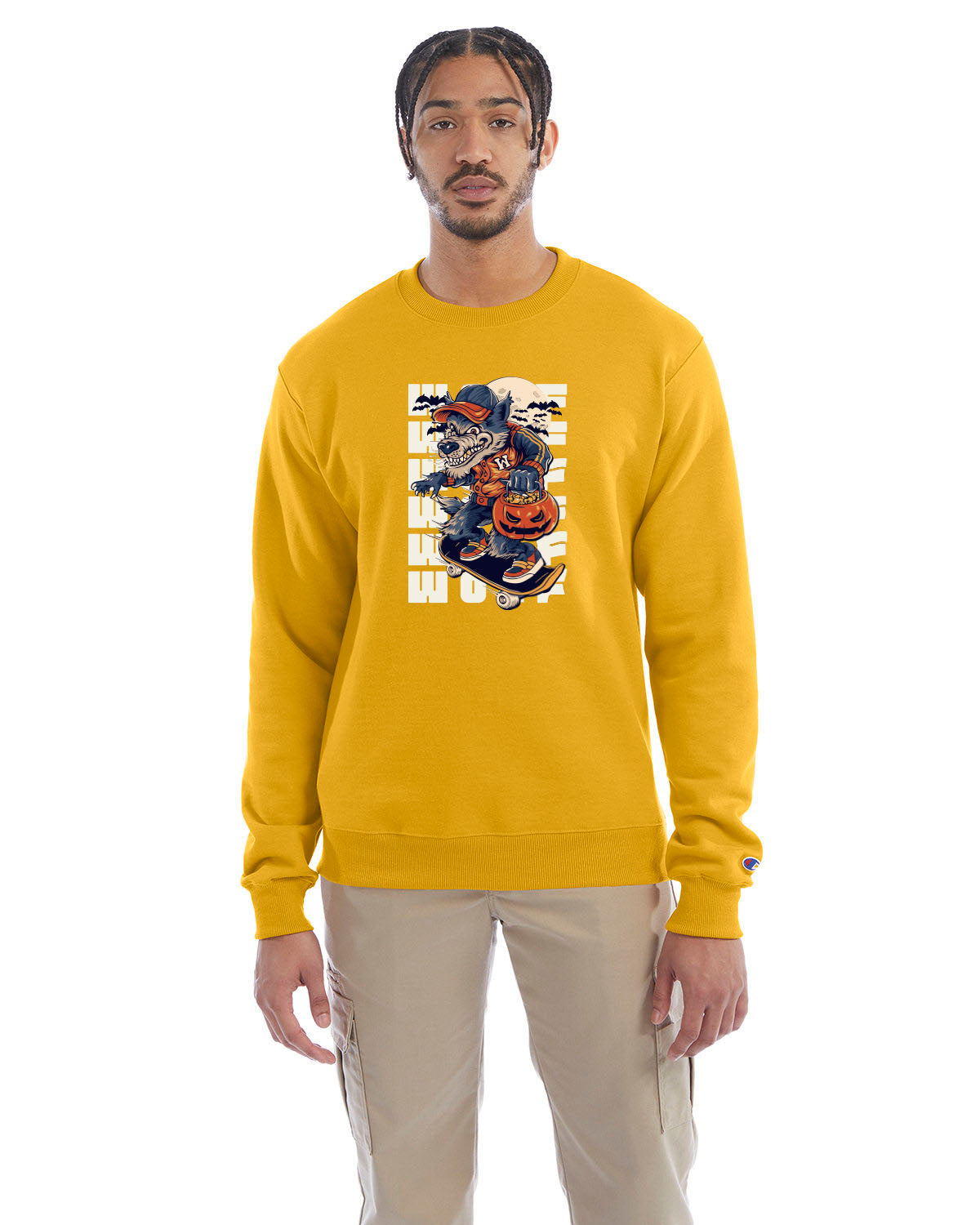 Gold crewneck sweatshirt with a Halloween-themed graphic of a cartoon werewolf skateboarding with a pumpkin basket, worn by a model in beige pants.