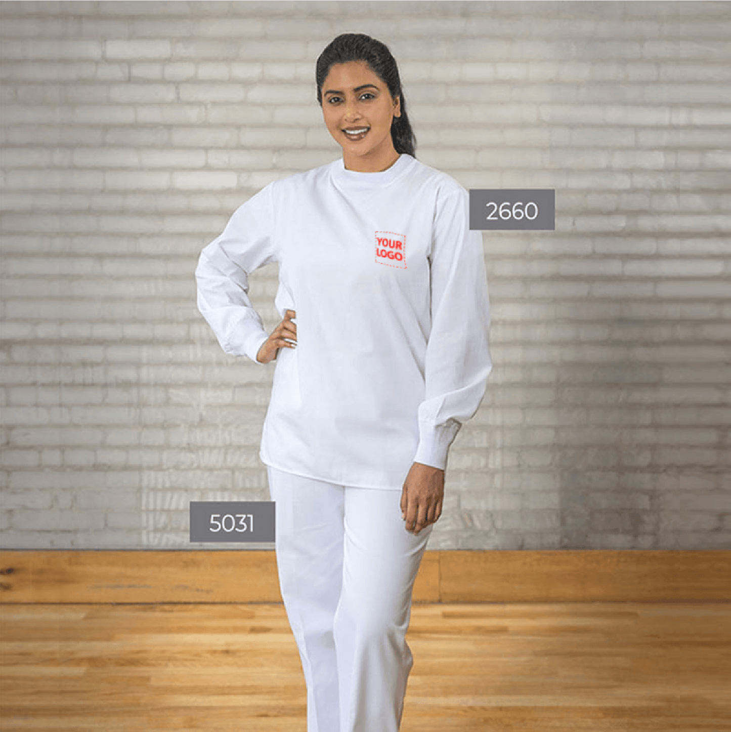 Female model wearing a white crew-neck scrub set with long sleeves and custom logo on the chest.