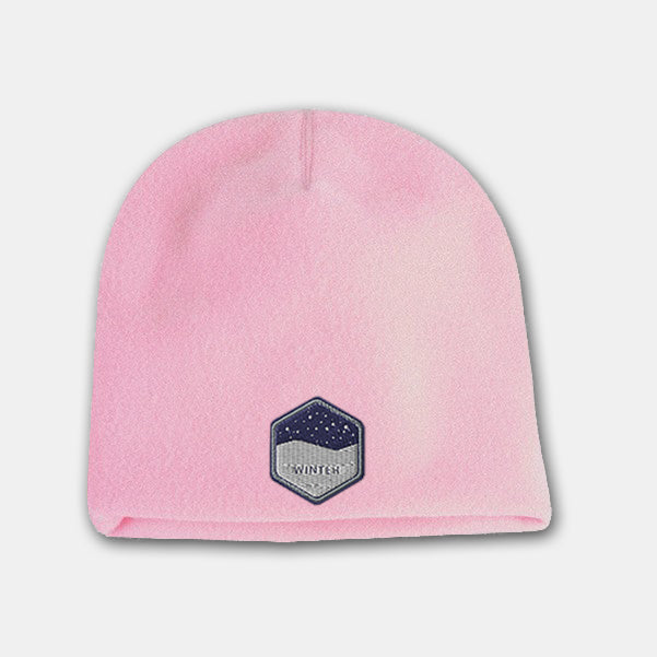Pink deluxe fleece beanie with a hexagon-shaped embroidered patch featuring a snowy night design on the front.