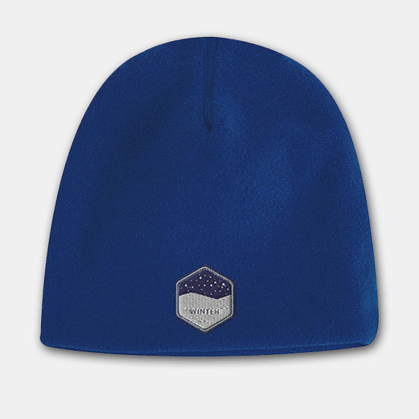 Royal blue deluxe fleece beanie with a hexagon-shaped embroidered patch featuring a snowy night design on the front.