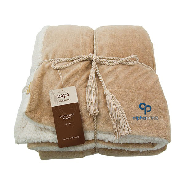 Deluxe lambswool throw blanket in camel, featuring a matching rope tie, soft white fleece lining, and embroidered logo