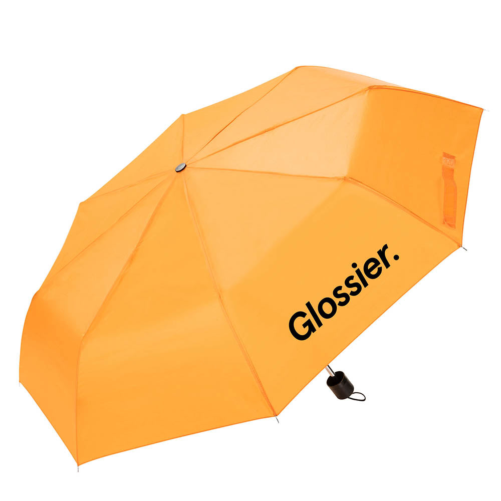 Bright orange umbrella with the “Glossier.” logo printed in black on one panel, featuring a compact black handle with wrist strap