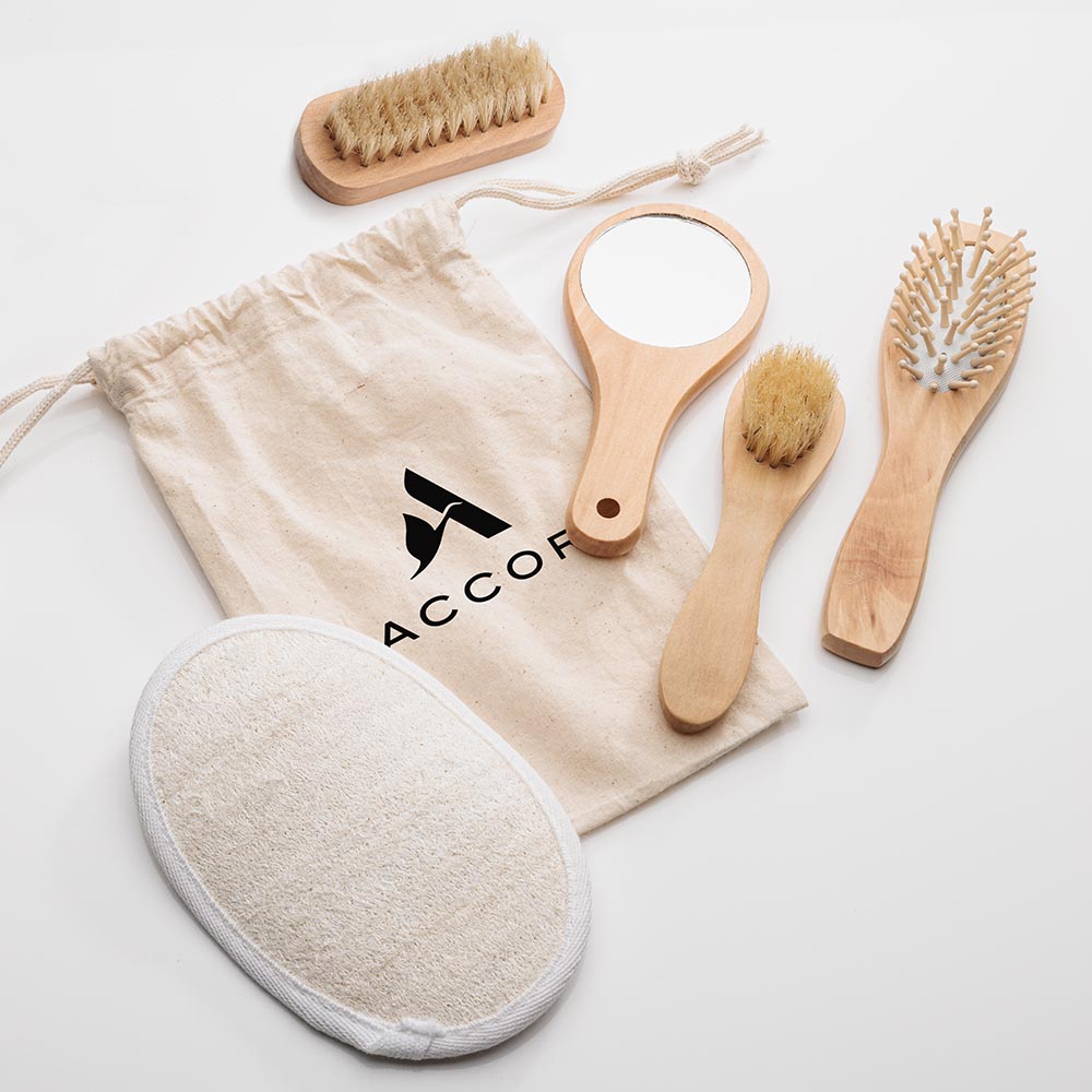 Natural relaxation spa kit with custom cotton drawstring bag, featuring wooden-handled mirror, brushes, comb, and loofah pad.