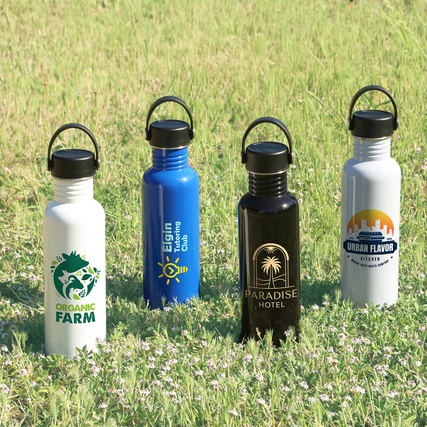 Four custom logo water bottles in white, blue, black, and gray on grass