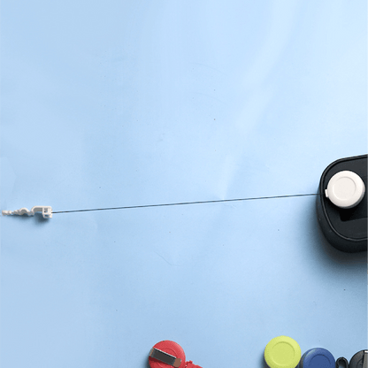 Retractable badge reel with extended nylon cord and white clip end, shown pulled out from a black reel housing against a light blue background.