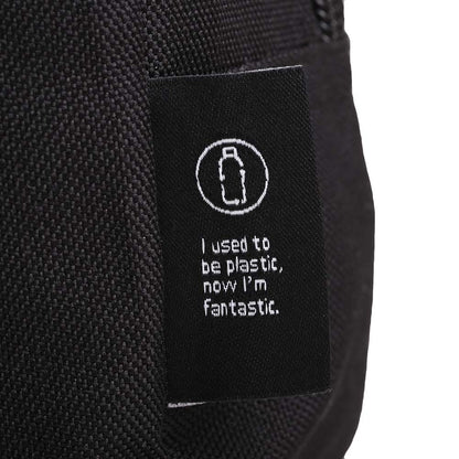 Close-up of eco-friendly fabric tag on a black toiletry bag with bottle icon and text: 'I used to be plastic, now I’m fantastic.'