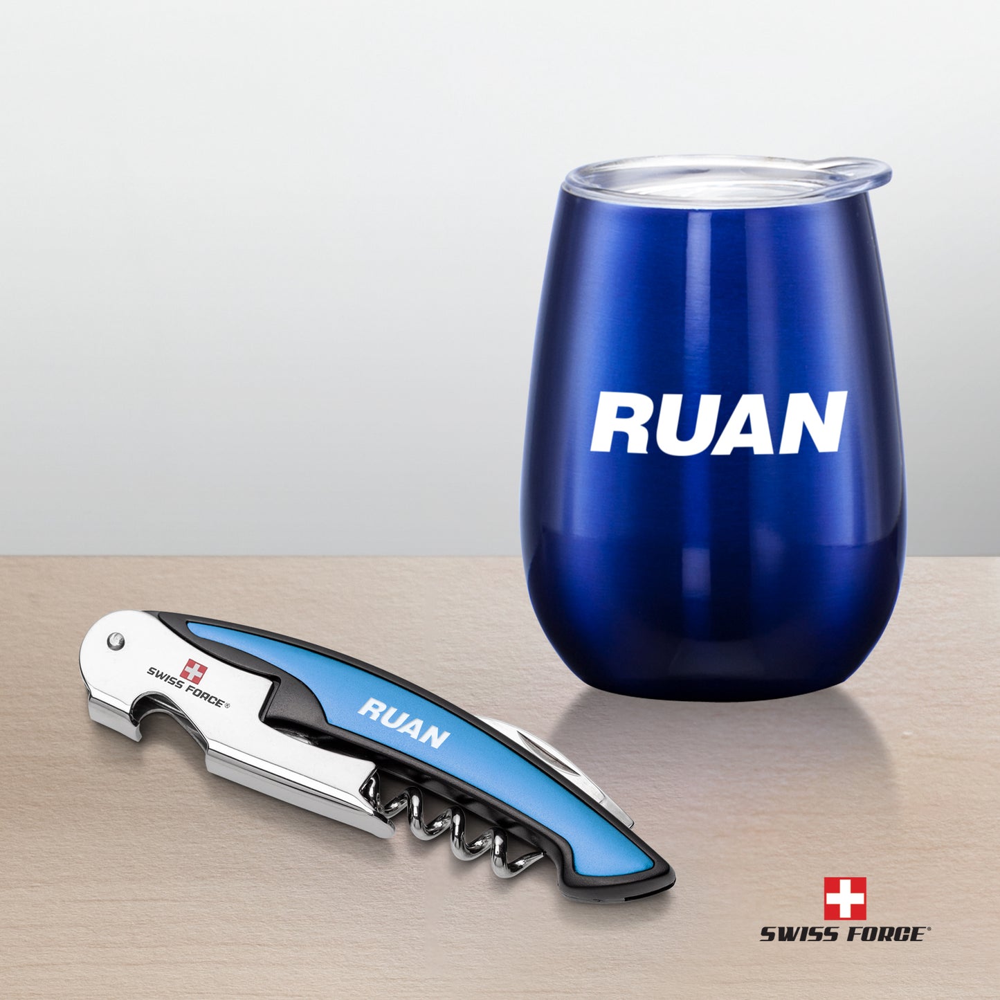 Swiss Force® Rosette Wine Gift Set with a glossy blue wine tumbler featuring a white 'RUAN' logo and a matching corkscrew with blue accents and engraved branding, placed on a wooden surface.