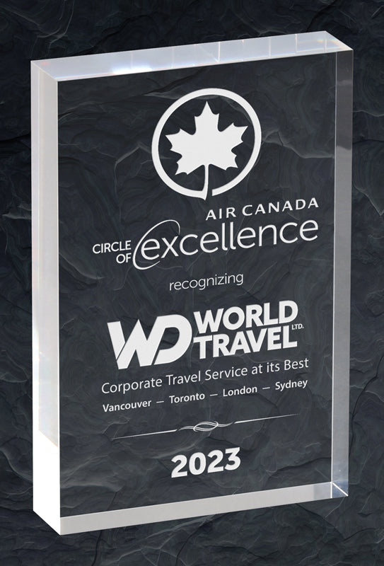 Clear rectangular glass award engraved with "Air Canada Circle of Excellence," recognizing "World Travel Ltd." for corporate travel service, dated 2023.