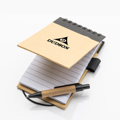 Eco-friendly spiral notepad with kraft paper cover, black binding, and lined pages, shown open with matching black and kraft pen placed on top.